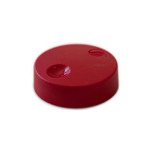 Introducing the Waldorf - Wave - Red Knob: a small, round, flat, red plastic knob featuring two distinct dimples on its surface—one larger and circular, the other smaller and textured. The knob is showcased against a plain white background.