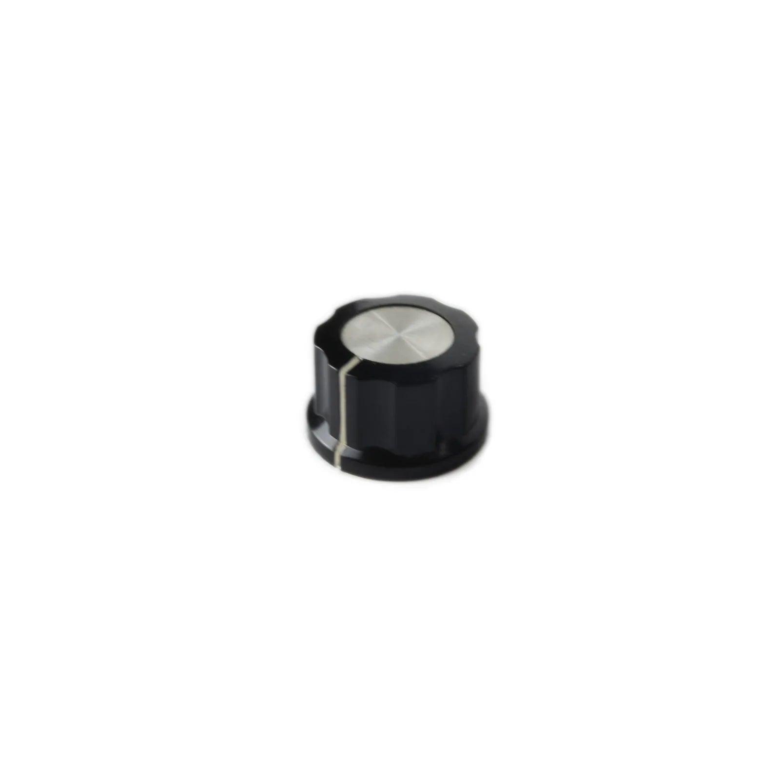Small black synthesizer knob with silver metal top and white alignment line on white background